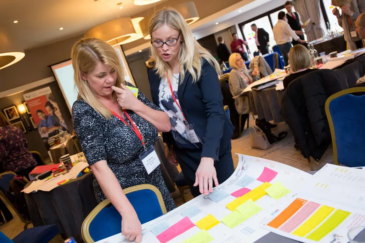 Business owners planning on a table covered in sticky notes at a workshop