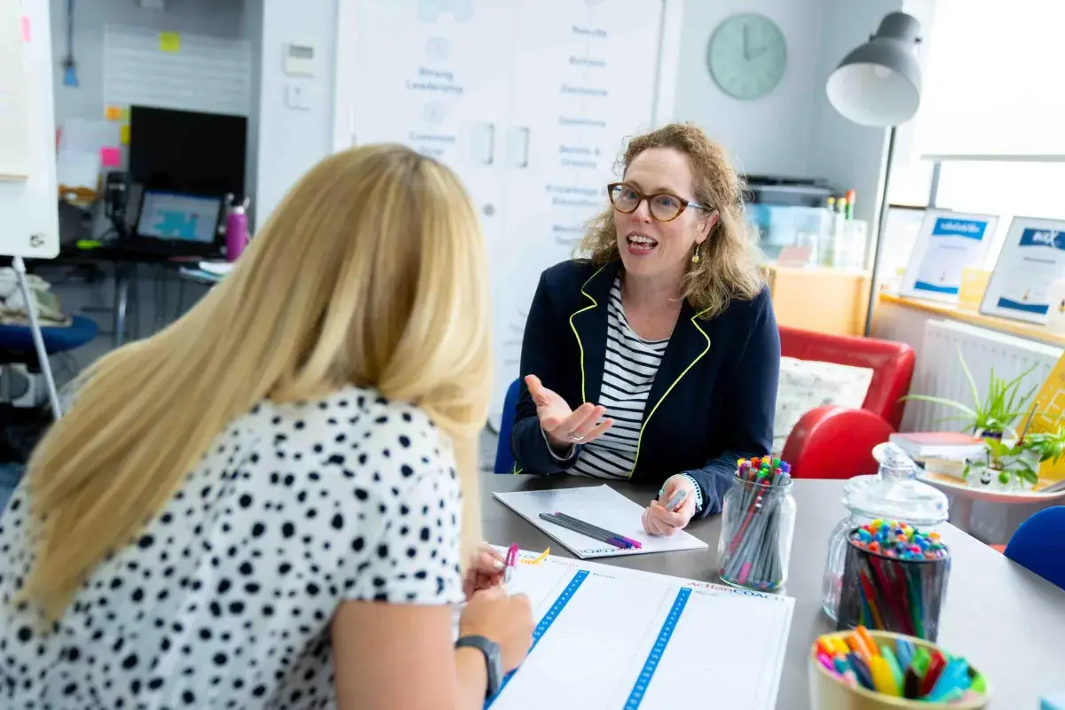 A business coach in conversation with a business owner at a table