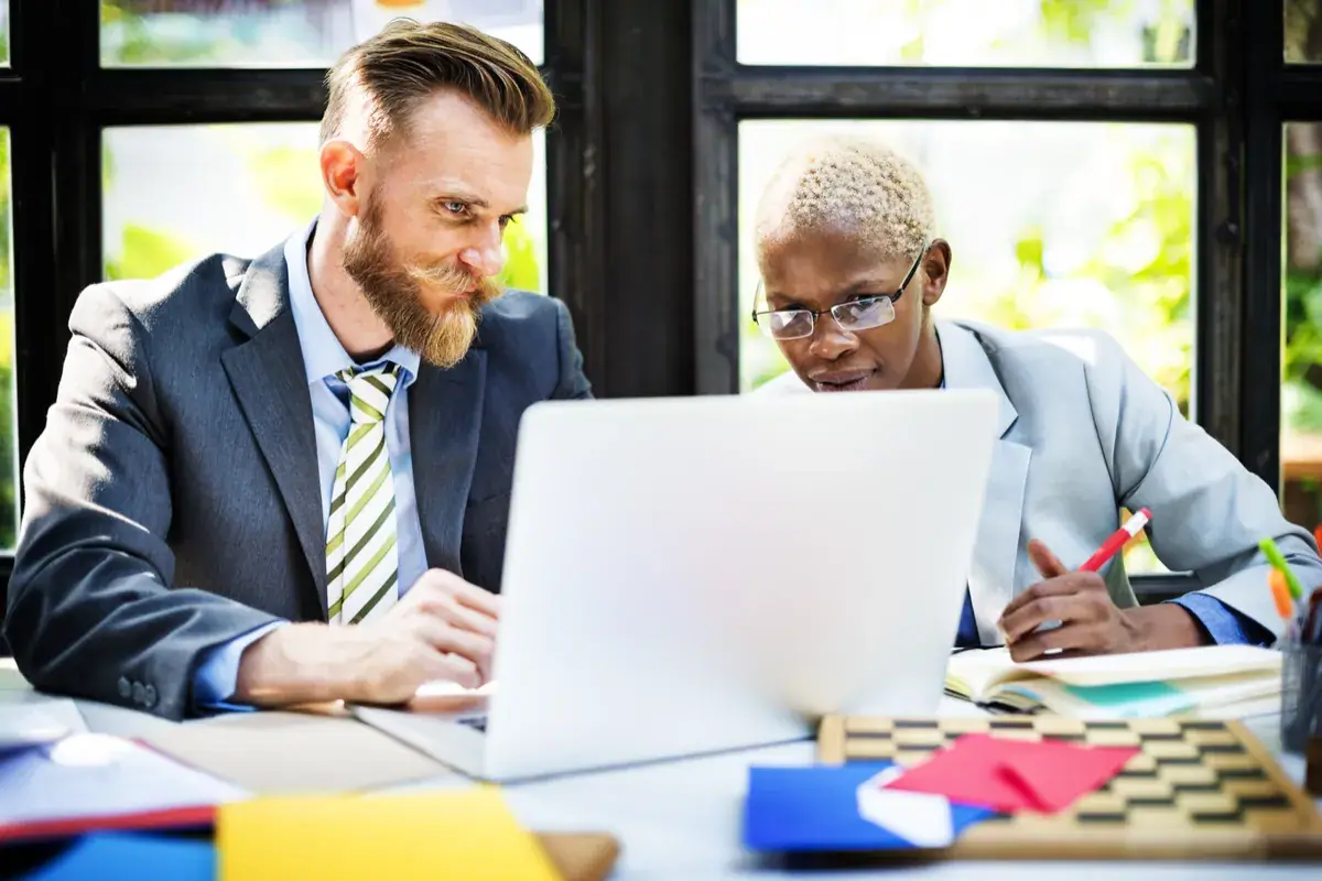 A business owner and coach reviewing a plan together at a laptop